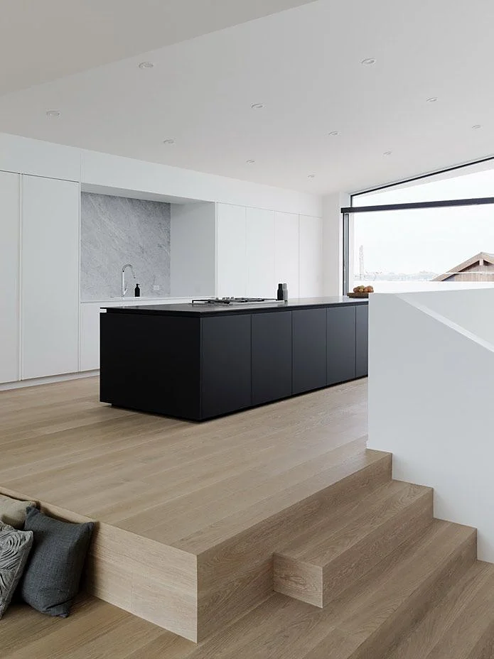 Black matt kitchen island with white floor-to-ceiling tall units and a marble niche