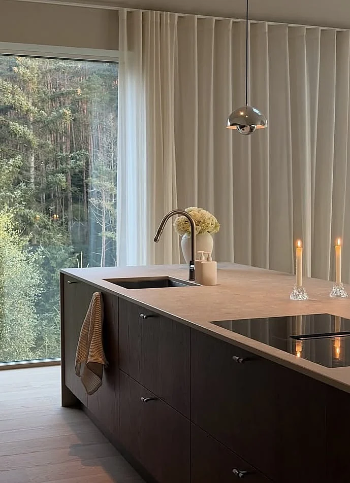 Dark wood kitchen island with a natural stone worktop, undermount sink and flush induction hob