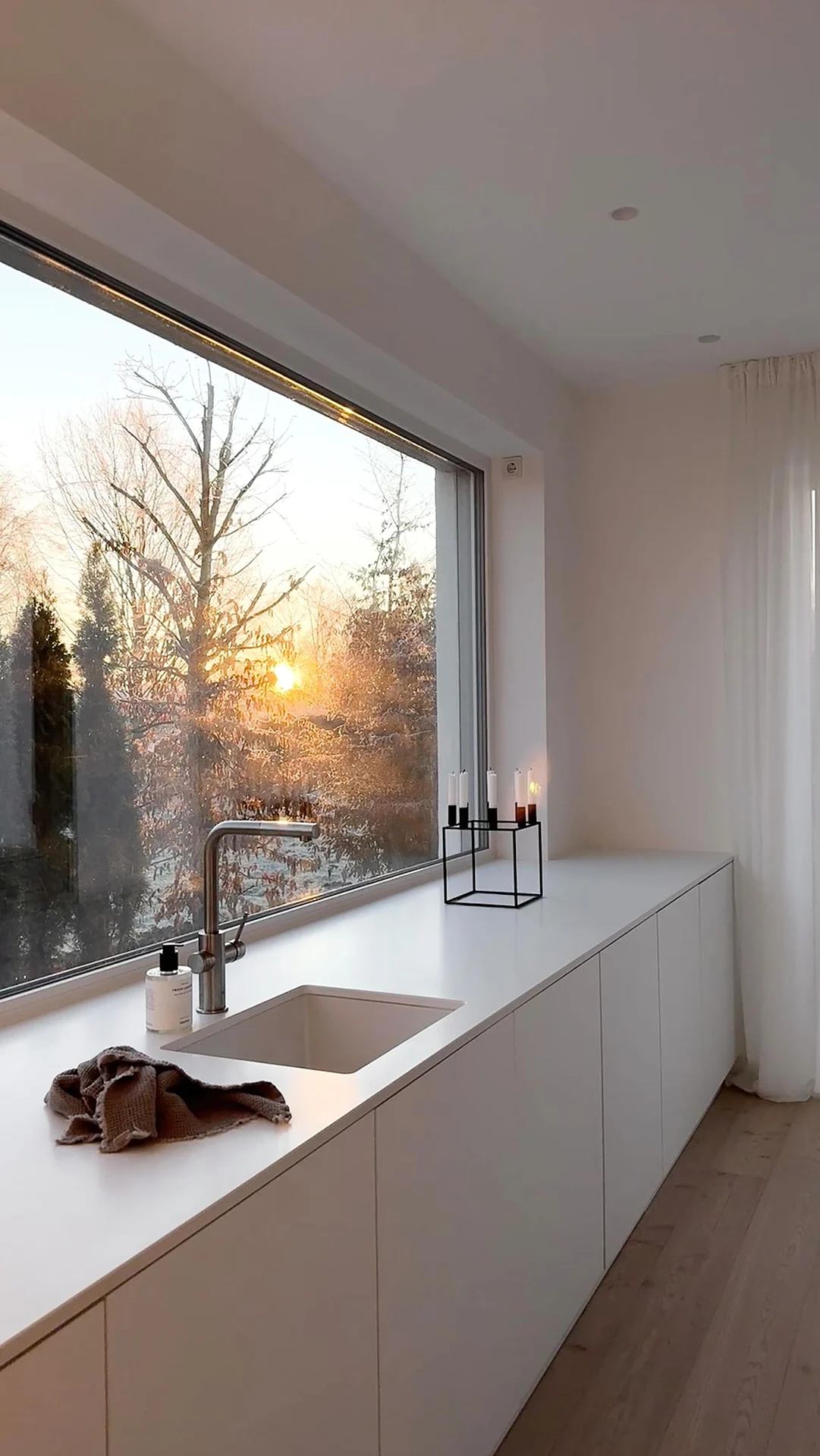 White handleless kitchen run with undermount sink in front of a large panoramic window